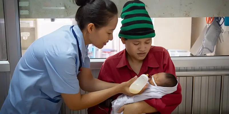 Nurse Helping To Feed The Newborn